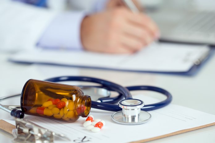 Pills and stethoscope laying on clipping board
