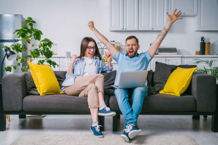 Young couple celebrating money win after betting online at bookmaker's website
