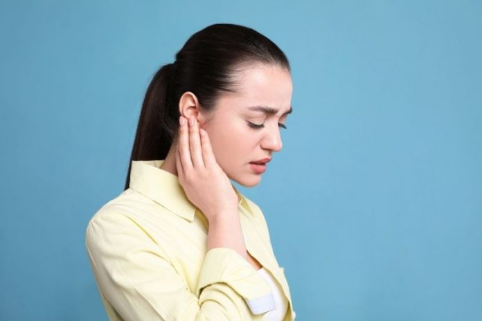 Young,Woman,Suffering,From,Ear,Pain,On,Light,Blue,Background.